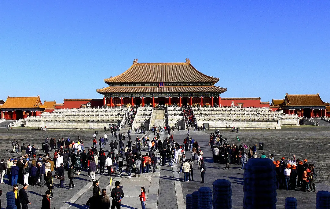 Visitors crossing the stone courtyard in front of the Hall of Supreme Harmony on a clear day