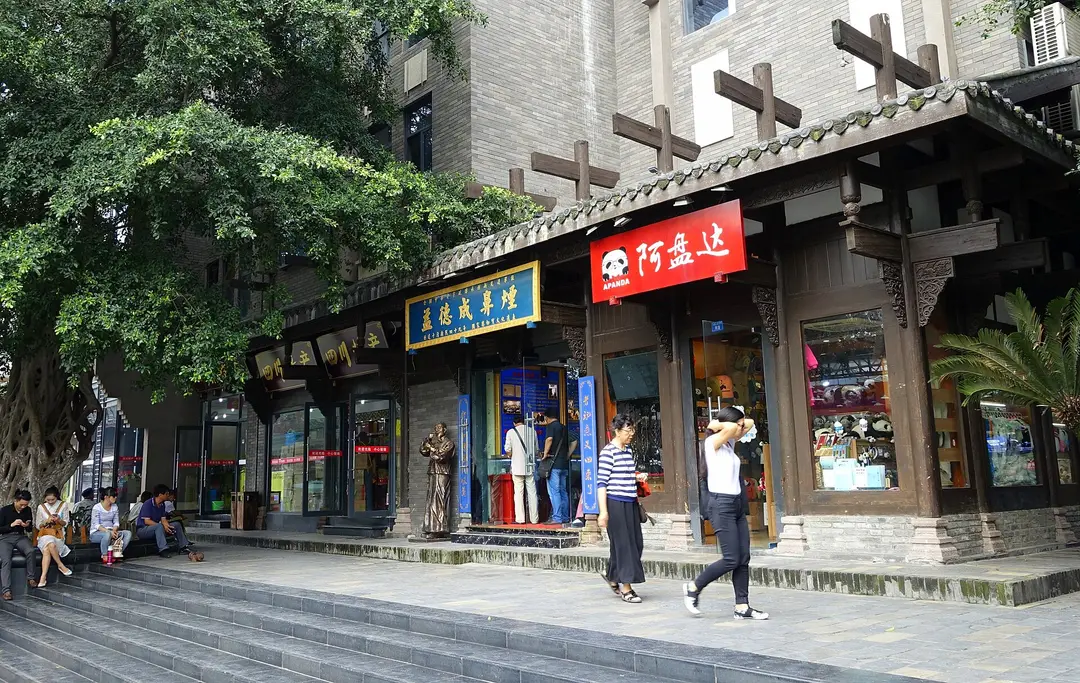 Shoppers walking past traditional-style shopfronts under a tiled roof in Kuanzhai Alley, Chengdu