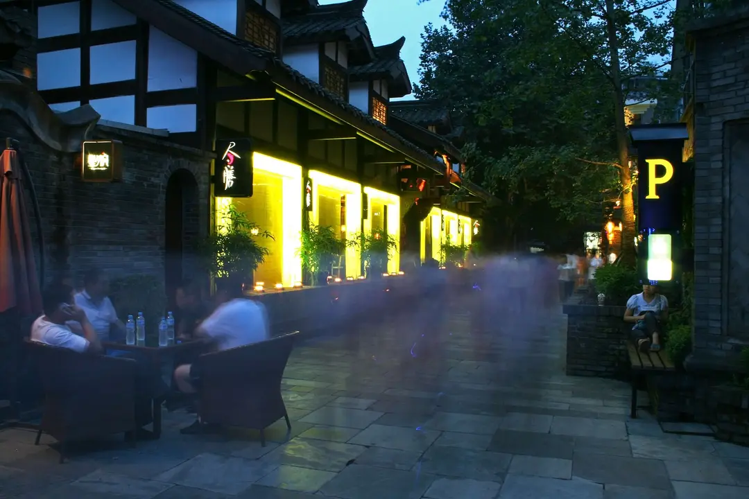 Narrow Alley in the evening, with lit shopfronts and people seated at outdoor tables