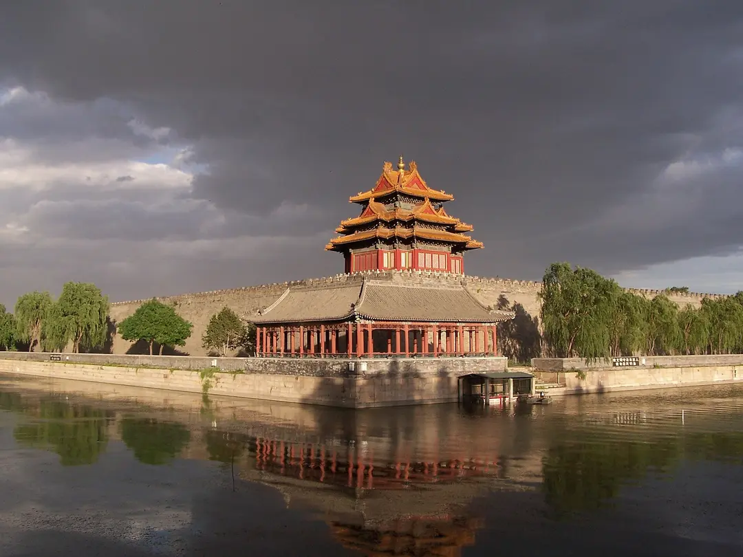 Northwest corner tower of the Forbidden City reflected in the moat under a dark evening sky