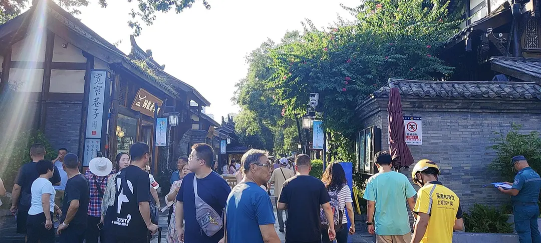 Visitors walking along a lane of grey-brick courtyard houses with wooden fronts at Kuanzhai Alley