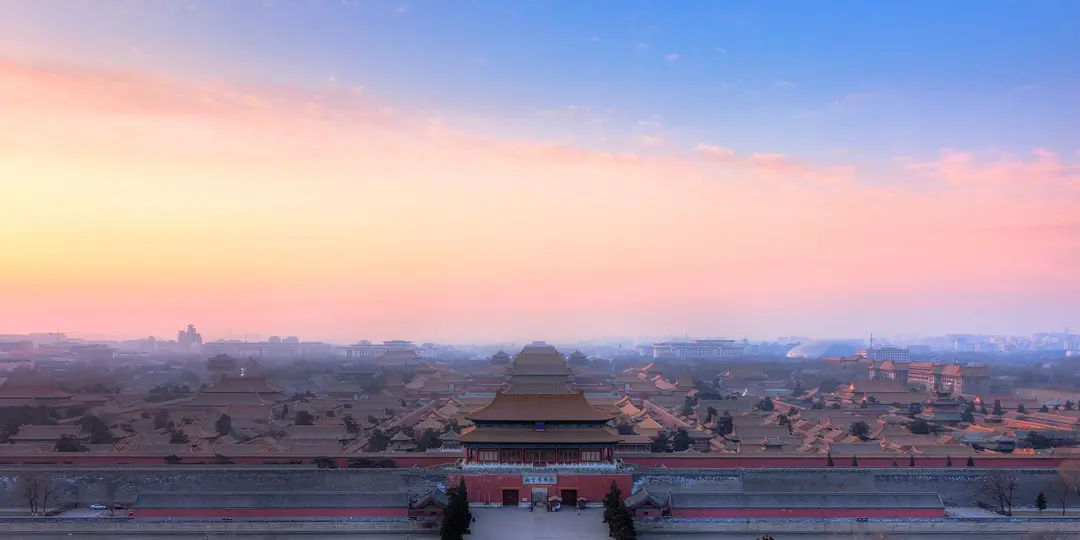 The roofs of the Forbidden City seen from Jingshan hill at sunrise, under a pink and blue sky