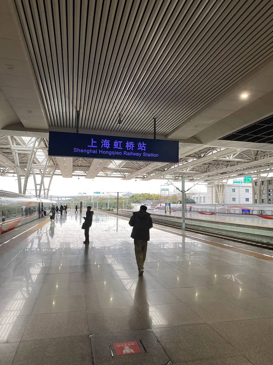 Passengers on a platform at Shanghai Hongqiao station beside a Fuxing high-speed train