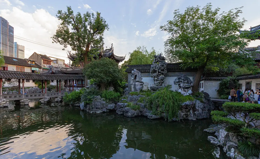 A rockery of pitted stone and old trees reflected in a pond inside Yu Garden